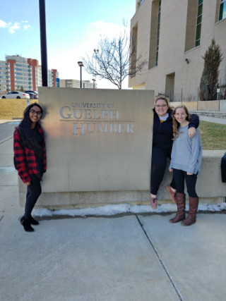 Three students posing in front of Guelph-Humber building sign